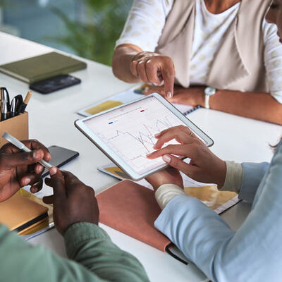 Group of people in a meeting looking at a tablet with data